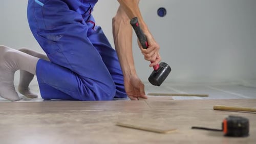 Man Installing Flooring with Mallet Indoors