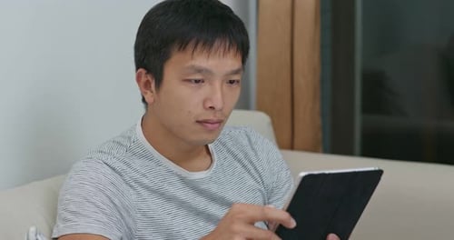 Man Relaxing At Home Uses Tablet Device