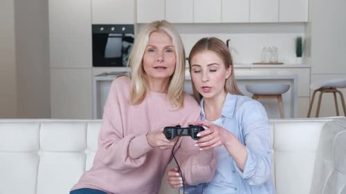 Women play video games together on a couch