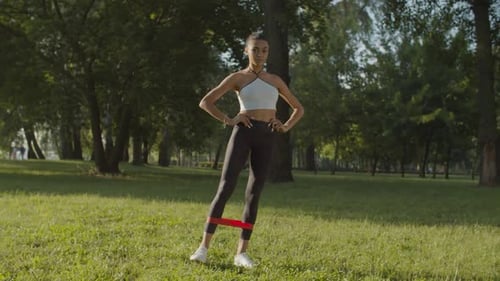 Woman Exercising Legs With Resistance Band in Park