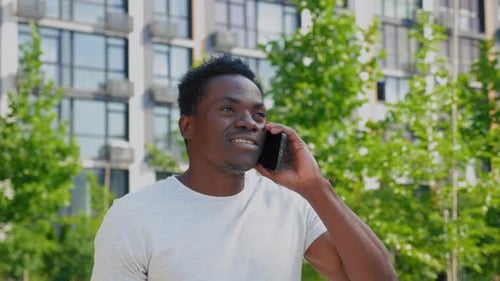 Portrait Smiling Positive Afroamerican Man Talking on Mobile Phone in Park