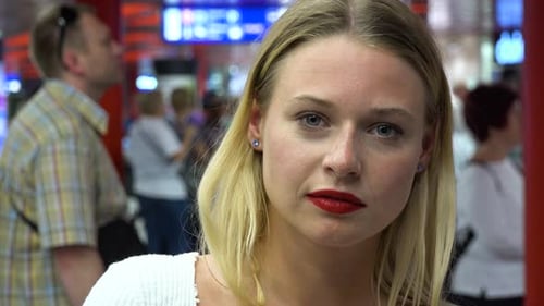 A Young Beautiful Woman Looks at the Camera in a Train Station Building - Face Closeup