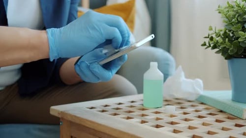 Close-up of Male Hands in Gloves Wiping Smart Phone Gadget with Sanitizer Indoors