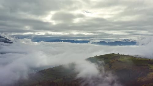 Fliegen Sie über Landschaften von grünen Hügeln unter einer Schicht weißer und flauschiger Wolken