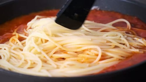 Spaghetti Being Tossed in Tomato Sauce in Pan