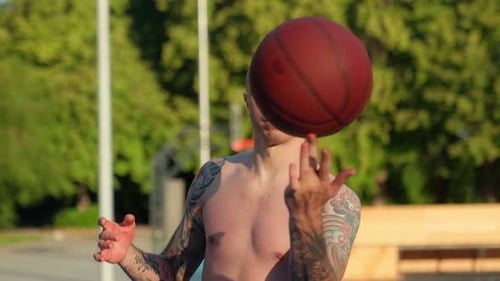 Shirtless Tattooed Man Spinning Basketball on Finger