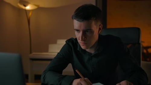 Caucasian Man Learning Online Course Behind Laptop at Night
