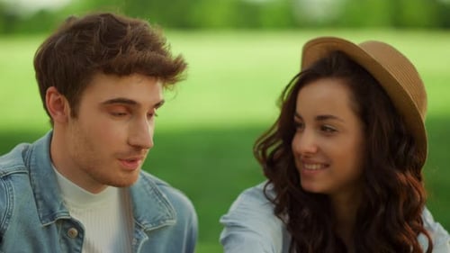 Cheerful Girl and Guy Having Picnic in Park. Man and Woman Laughing Outdoors