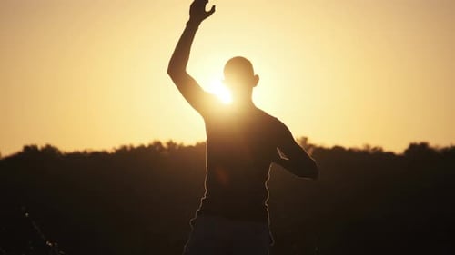 Man Silhouetted Reaching Upward at Golden Sunset