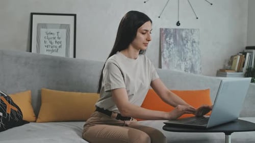 Young Woman Works on Laptop on Couch