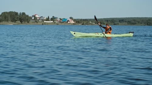 Man Kayaking on a Calm Lake During the Day