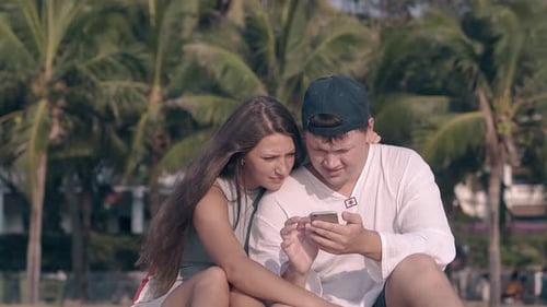 Couple Looking at Phone on Tropical Beach