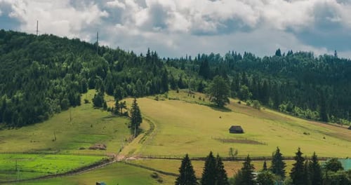 Country houses and hotels in rural area on the hill, clouds passing over the mountain range.