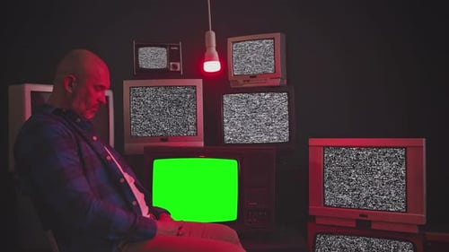 Man Sits Surrounded by Vintage TVs with Static