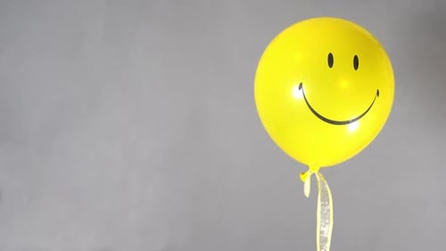 Single Yellow Balloon Against Gray Background