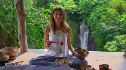 Woman Performs Sound Healing Session by Tropical Waterfall