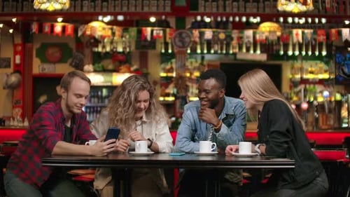 AfroAmerican Man with Friends in a Cafe Laughs and Spends Time in a Cheerful Company and Smiling