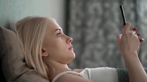 Woman Lying Down Using Smartphone in Bed