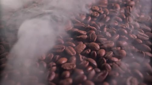 Ароматные кофейные зерна в процессе обжарки с присутствием небольшого количества дыма