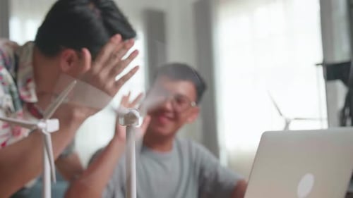 Un profesor y un alumno de Blur Happy utilizan una turbina eólica eléctrica para programar una computadora portátil