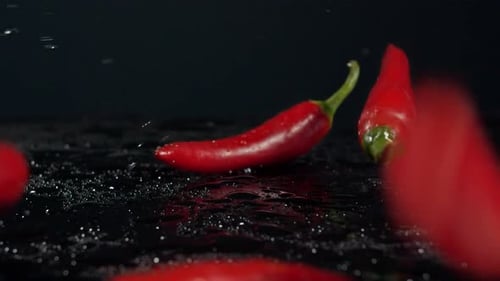 SLO MO Red Chilies Bouncing Off Water Covered Black Surface