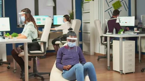 African Employee Holding Tablet Sitting on Armchair in Office Room