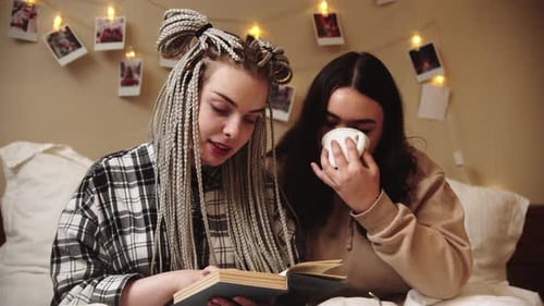 Two Friends Reading a Book Together in Bed