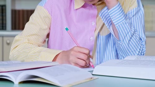 Closeup of Female Hands Writing with Pencil in Notebook Books on the Table