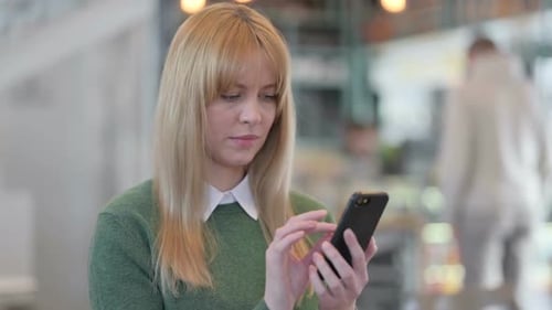 Blonde Woman Using Smartphone Indoors, Close Up