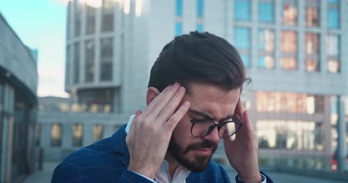 Stressed Young Man in Glasses Suffering From Muscles Tension Having Painful Head Feelings Due to