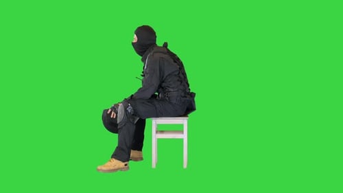 Policier anti-émeute assis avec son casque éteint se reposant sur un écran vert Chroma Key