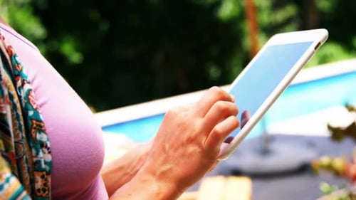 Girl using mobile digital tablet near pool side