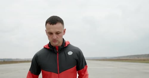 Young Fit Sporty Man Working Out Jogging Towards the Camera on a Cloudy Day on a Road in the