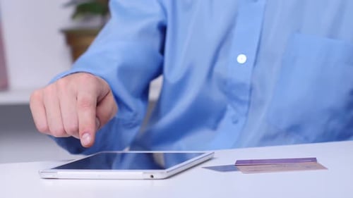Man Pays for an Online Purchase with a Tablet and Credit Card. Black. Close Up