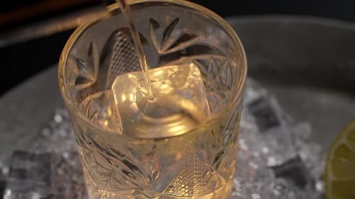 Whiskey is Being Poured in Slow Motion to the Ice Cube in the Spinning Glass Full Prores HQ 240 Fps