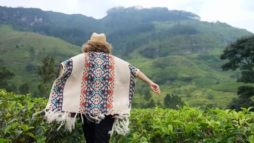Mujer feliz y libre huyendo en una plantación de té en las montañas