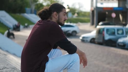 Portrait of Young Attractive Arab Man Sitting on the Stairs in Park at Sunset