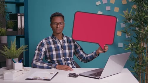 Young Adult Holding Speech Bubble at Office Desk