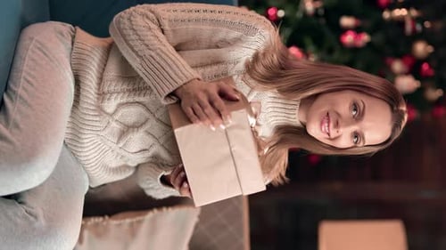Woman Holding Christmas Present on Couch at Home