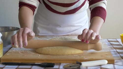 Dough Flattened with Rolling Pin on Cutting Board