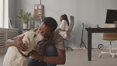 Cheerful Man Playing with Dog in Pet Friendly Office