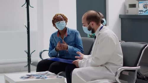 Doctor Consulting Patient With Face Mask in Clinic