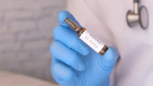 Doctor Hand in Gloves Holding Coronavirus Vaccine, Close Up