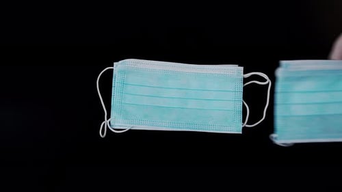 Hand Places Surgical Masks on Black Surface