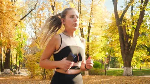 Woman Running in Autumn Park with Headphones