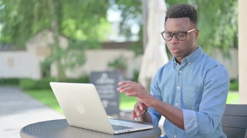 Young Man Typing on Laptop Outdoors
