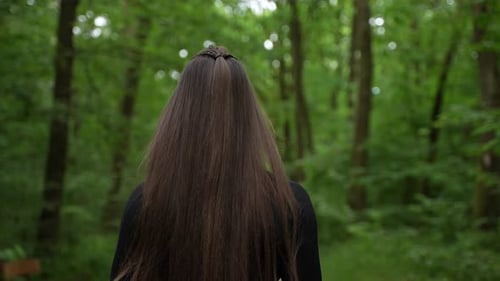 Woman Walks Through Green Forest on Trail