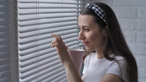 Woman Enjoying Coffee and Looking Out Window