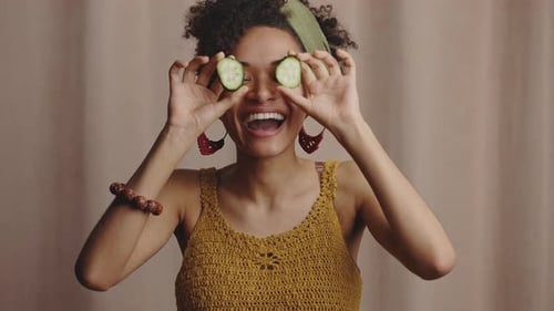 Smiling Woman Plays with Cucumber Slices in Studio