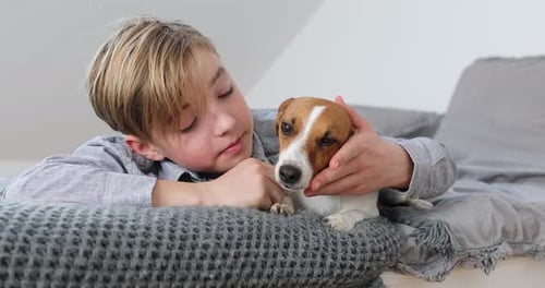 Boy Cuddling Dog Lying on Bed